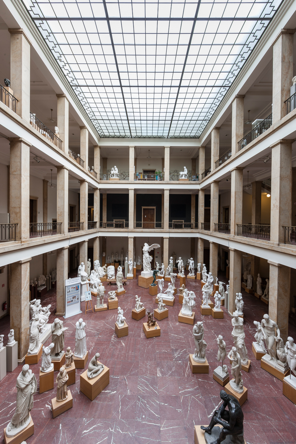 Panorama-Bild in den gesamten ersten Lichthof mit Skulpturen unten bis hin zum Glasdach an der Decke